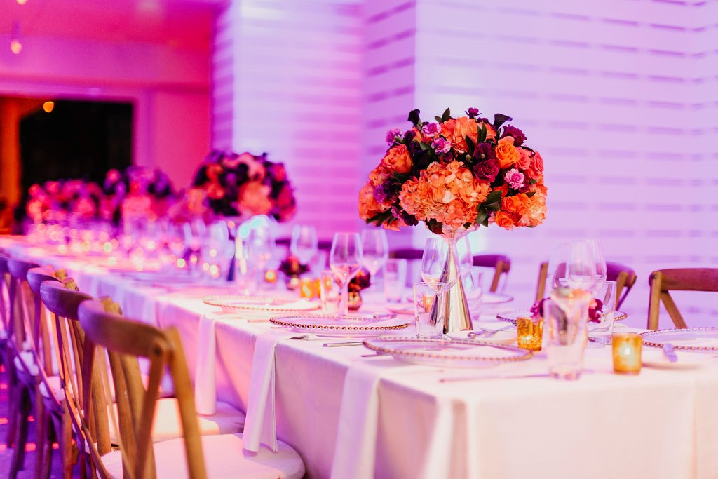 A long dining table set with white tablecloth, flowers, candles, and wine glasses.